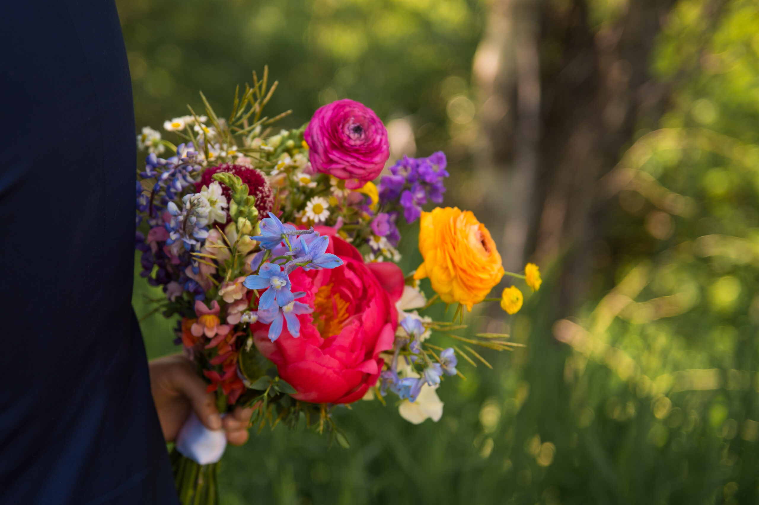 Bridal bouquet with native lupine, peony, ranunculus, and airy grasses at Wyoming mountain wedding