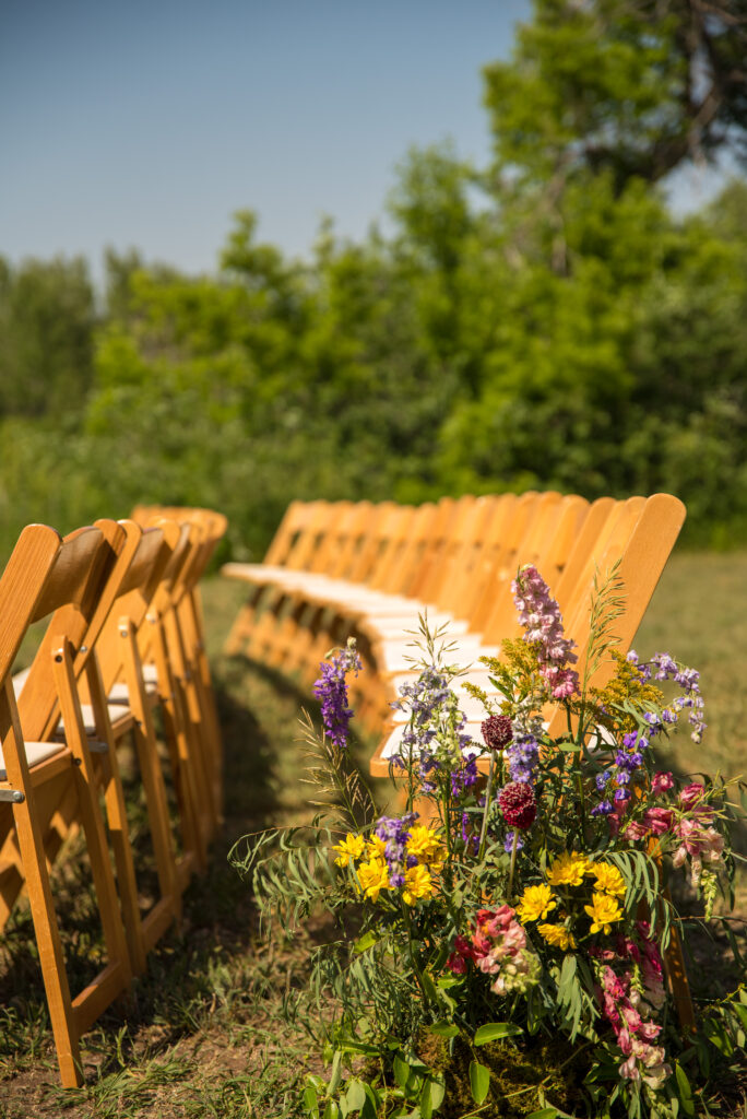 Color-blocked blooms lining ceremony aisle at Wyoming mountain wedding