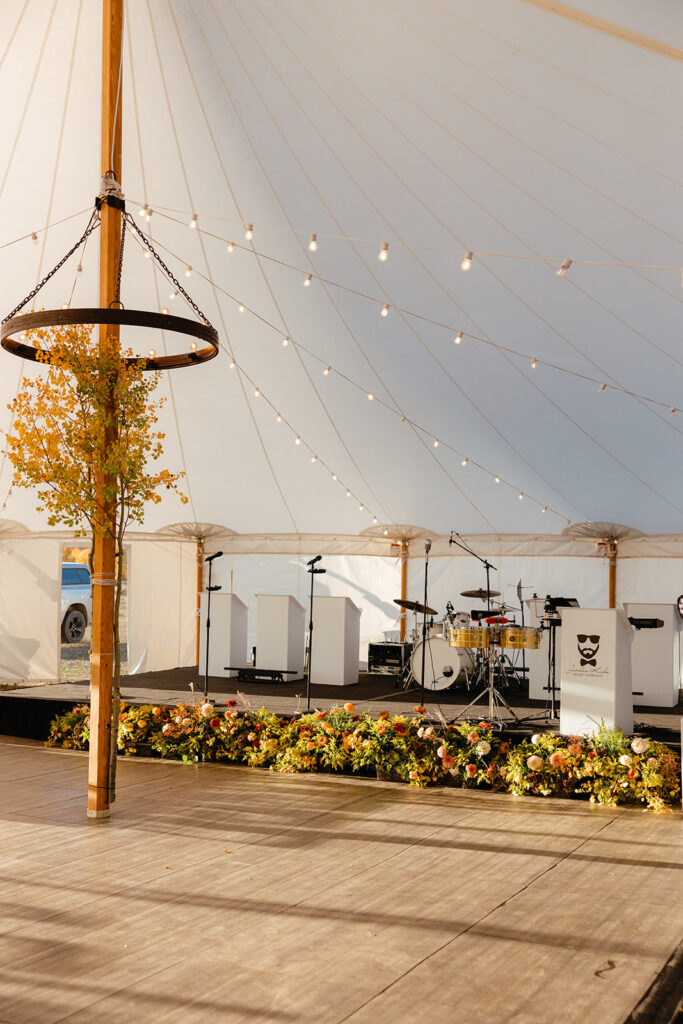 Fall tented wedding in Jackson Hole featuring aspens and flowers in front of the stage for the band.