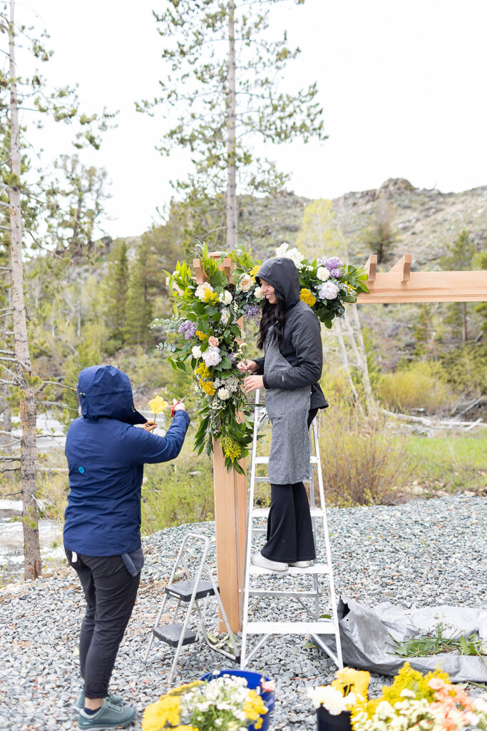 Setting a flower budget for your Jackson hole wedding is easy with Dandelion Floral. Here we are working on a ceremony arbor during an early summer snow storm.